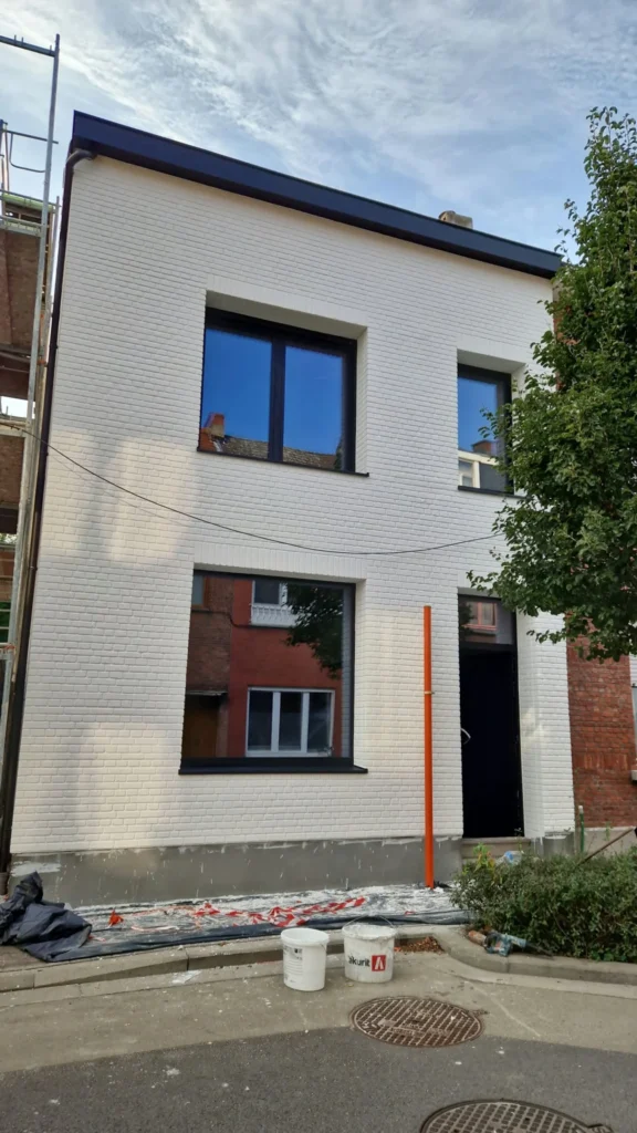 Maison de ville en imitation de brique badigeonnée en blanc, châssis noirs