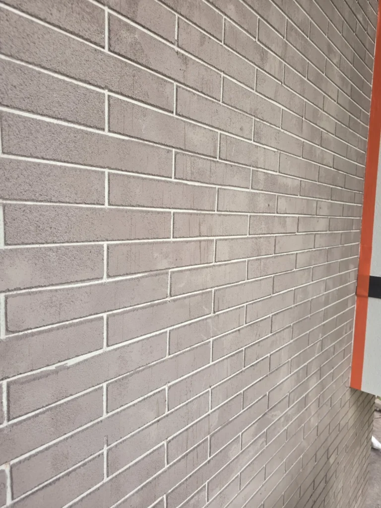 Façade en imitation de brique grise aux joints blancs tracés dans l'enduit