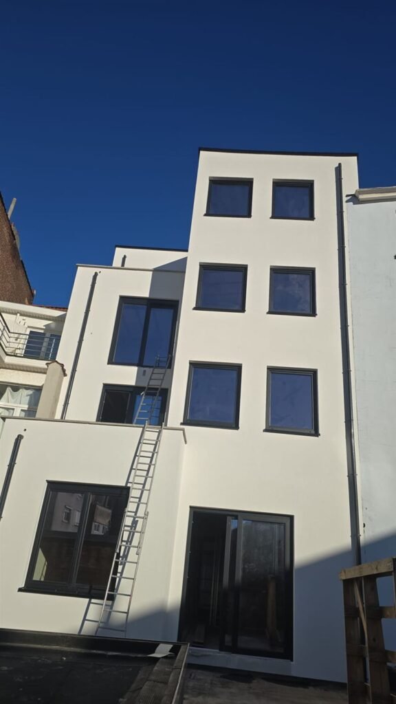 Façade arrière d'une maison de ville isolée et enduite en blanc, châssis anthracite